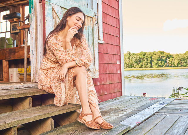 A woman sitting on steps wearing the Persa huarache in tan leather.