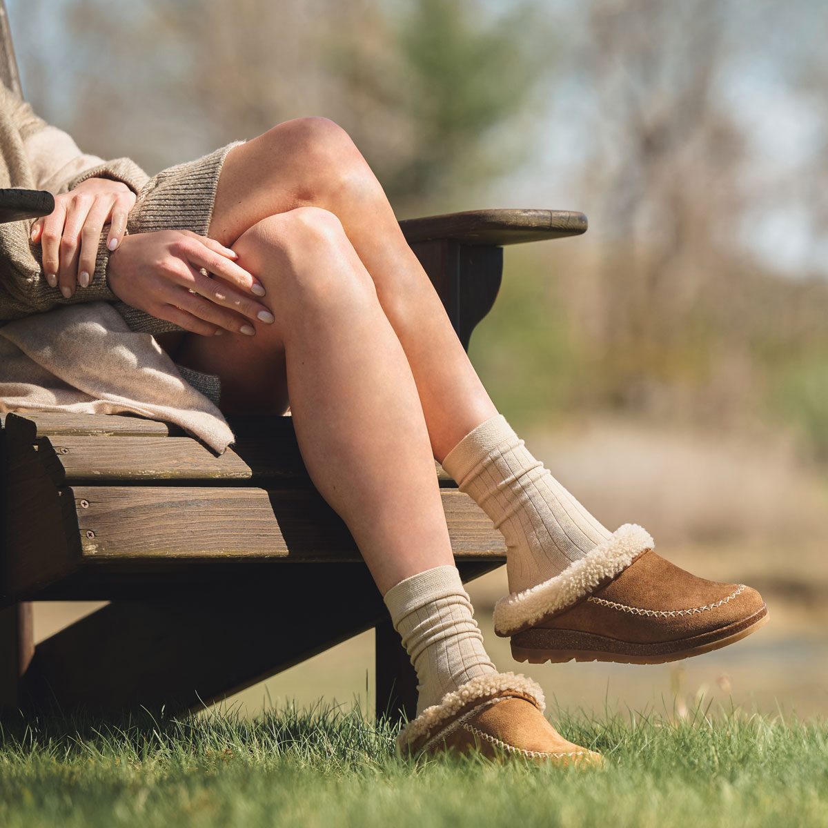 A woman wearing the Lucy slipper in brandy (tan) suede.