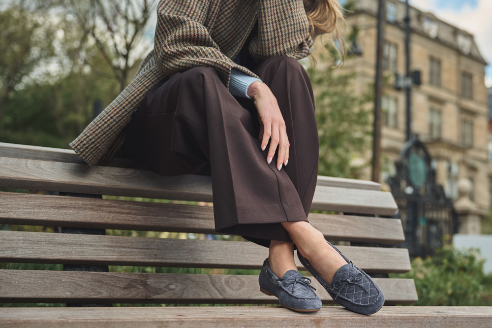A woman wearing the Tessie loafer in washed indigo (blue) suede.