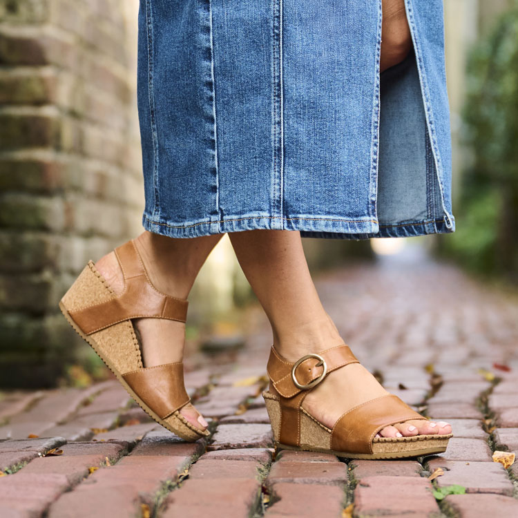 A woman wearing the Eldorah wedge sandal in brown.
